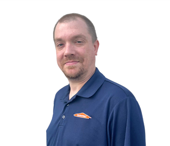Professional man with short hair wearing SERVPRO shirt against white backdrop 