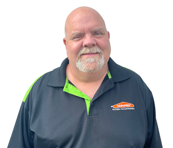 Man with gray beard wearing a black SERVPRO shirt against white backdrop
